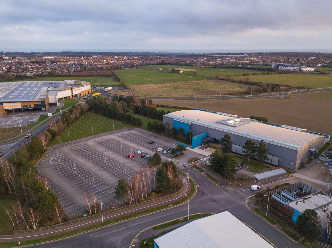 Wide aerial photograph showing the site and car park with the Westwood Cross retail cluster beyond